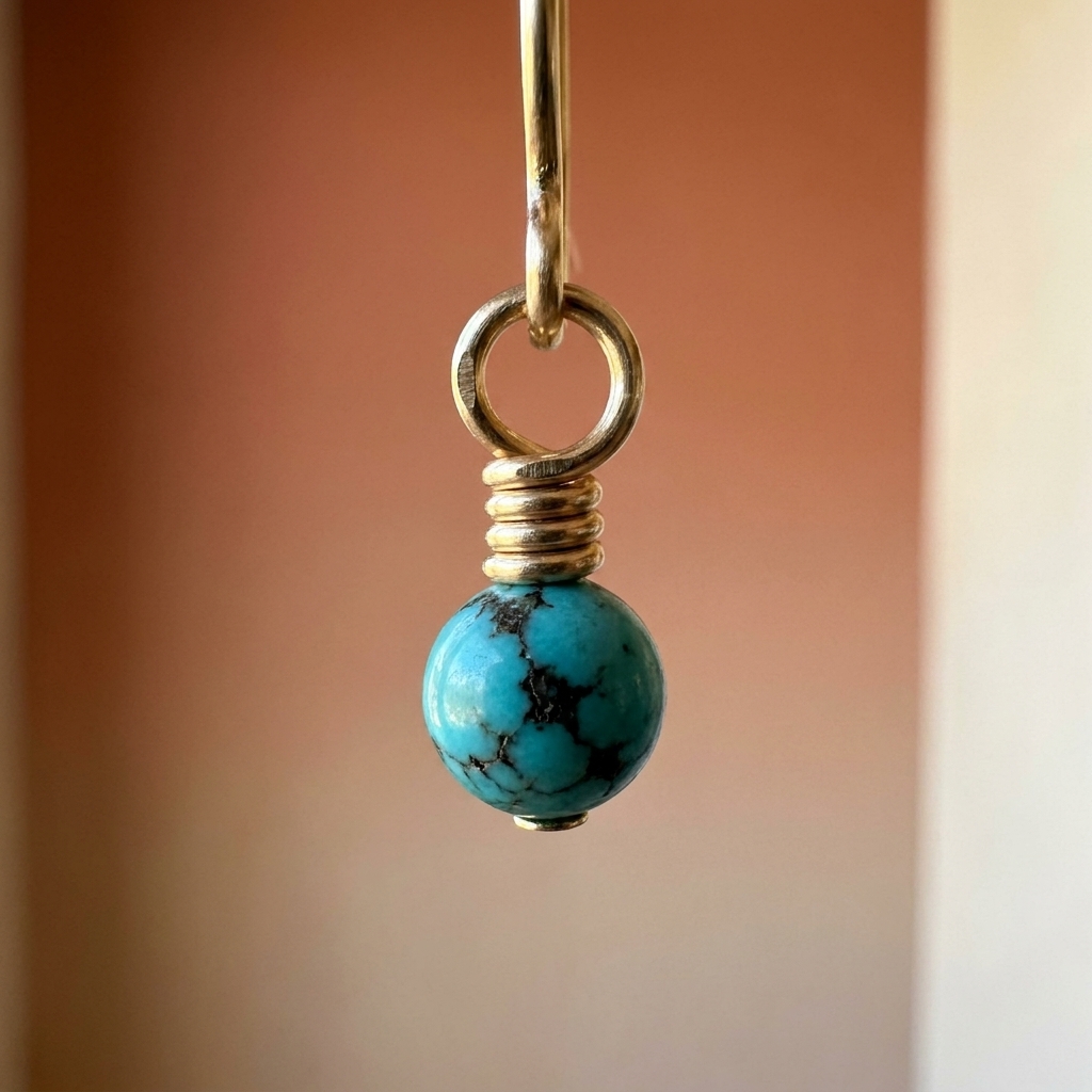 A detailed photo of a wrapped loop on a bead dangle, showing three tight wire wraps stacked neatly beneath a small round loop